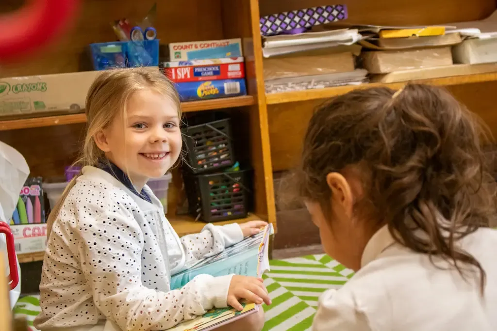 student smiling at the camera while holding a book